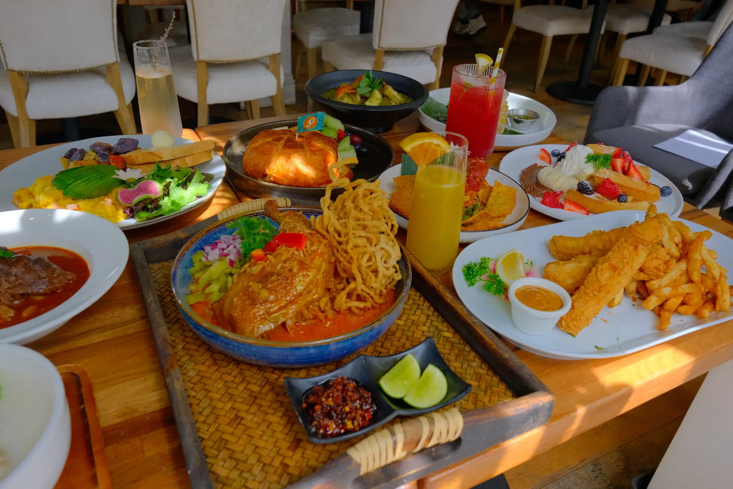 A table of brunch plates seen from above, with crispy noodles, fried rice and fish and chips