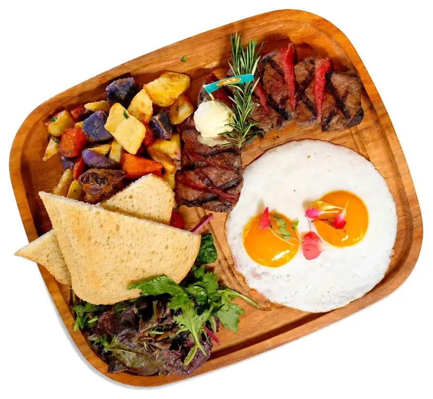 Grilled steak with roasted vegetables, a fried egg and tortilla on a wooden tray